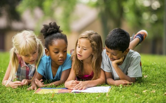 4 kids reading a book on the green - Enunciate 4 kids reading a book on the green
